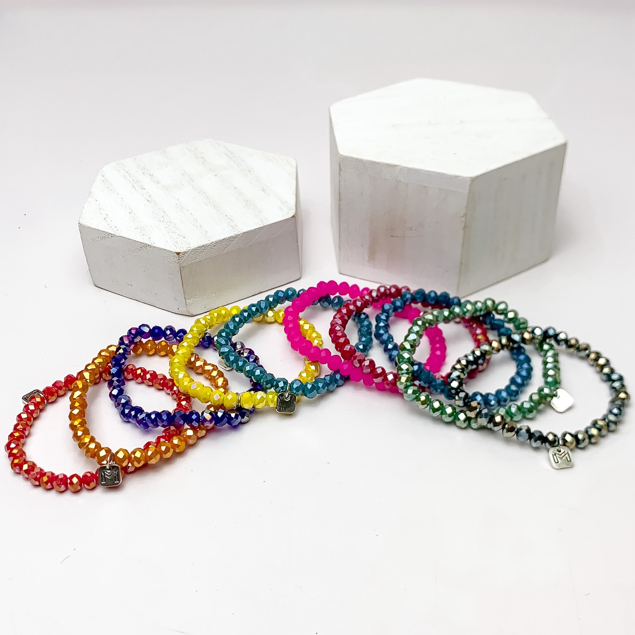 Set of Ten | Party Girl Crystal Beaded Bracelet Set in Dark Multicolor. These bracelets are pictured on a white background with two white podiums behind the bracelets.