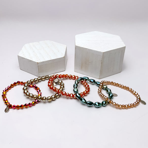 Set of Five | All Nighter Crystal Beaded Bracelet Set in Red and Blue Tones. These bracelets are pictured on a white background with two white podiums behind them.