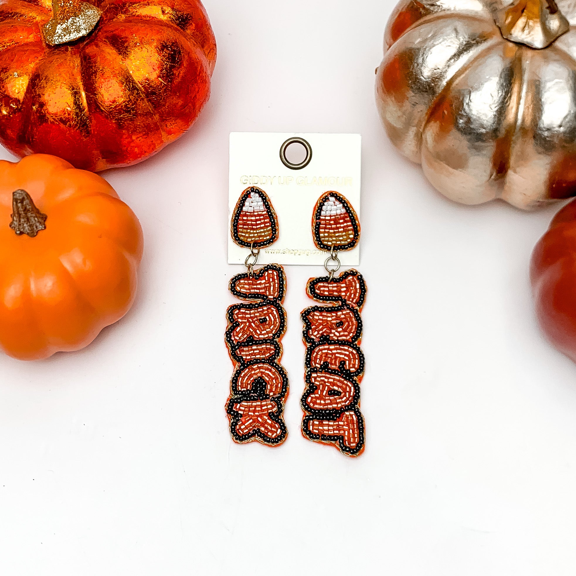Trick or Treat Halloween Beaded Earrings in Orange and Black. These earrings are on a white background with orange and silver pumpkins around them.