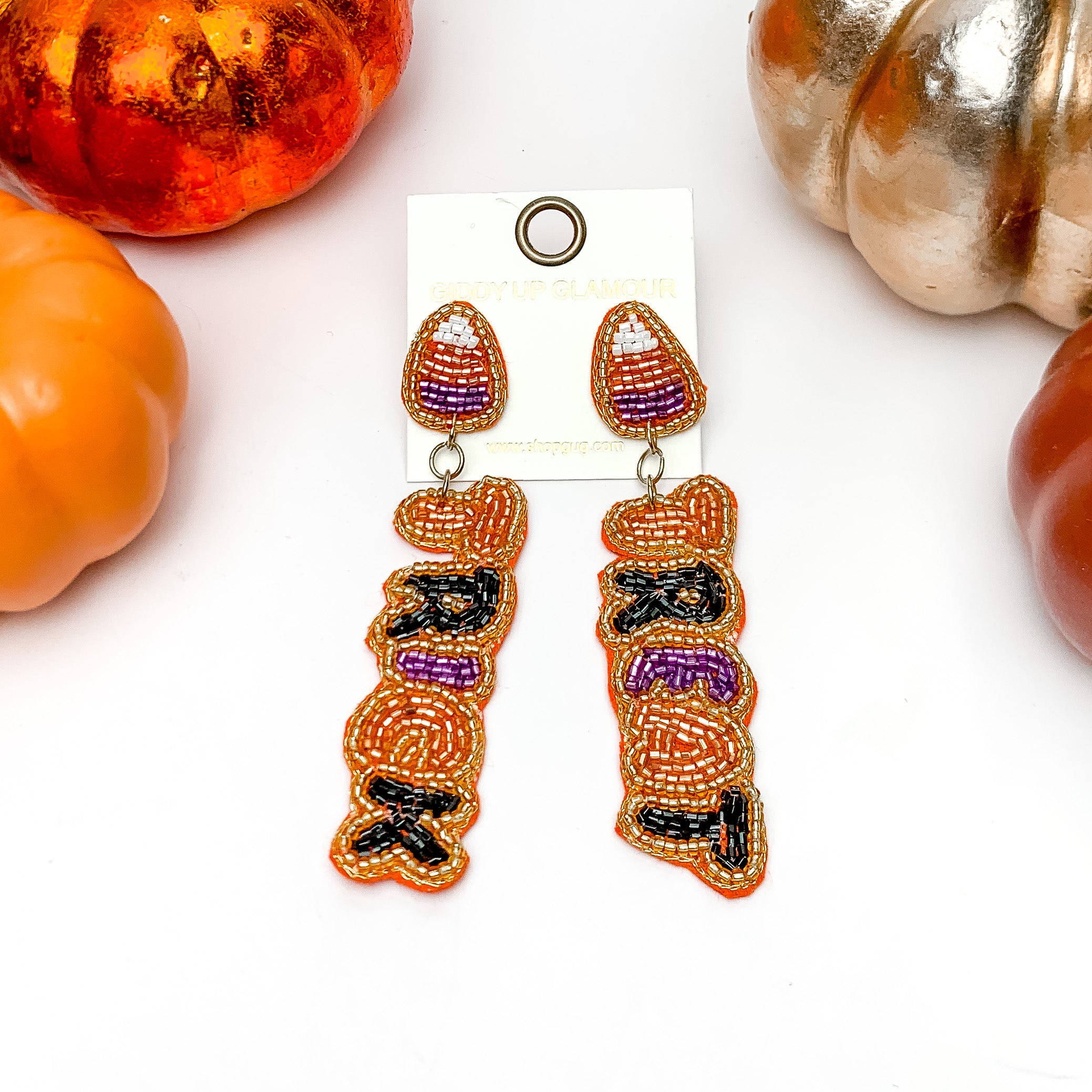 Trick or Treat Halloween Beaded Earrings in Orange, Purple, and Black. These earrings are on a white background with orange and silver pumpkins around them.