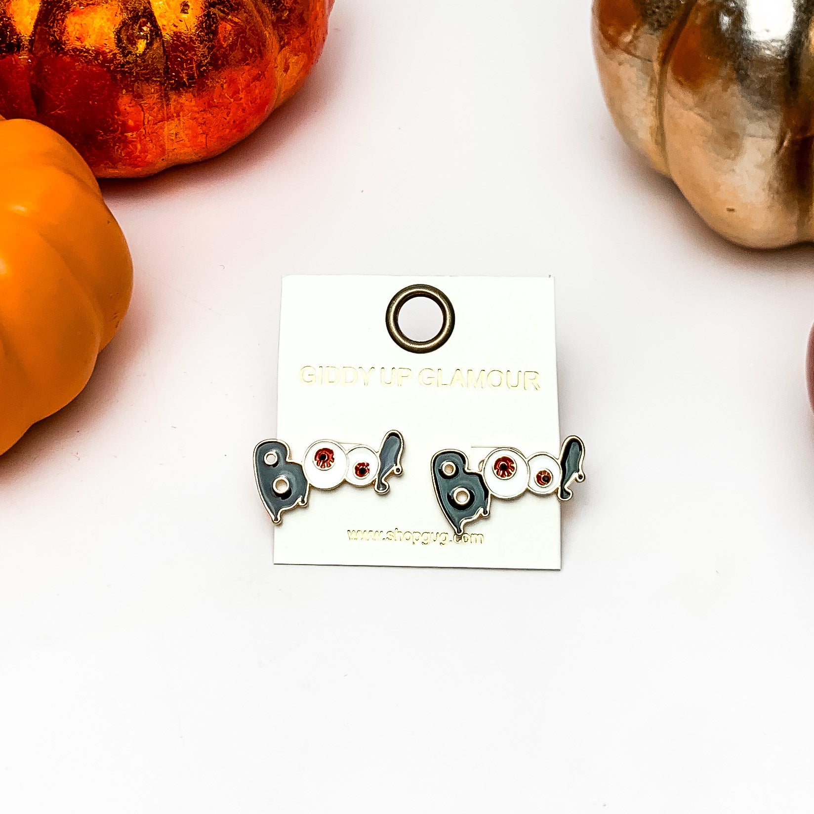 Boo Stud Earrings with Red Eyeballs in Black. These earrings are on a white background with orange and silver pumpkins around them.