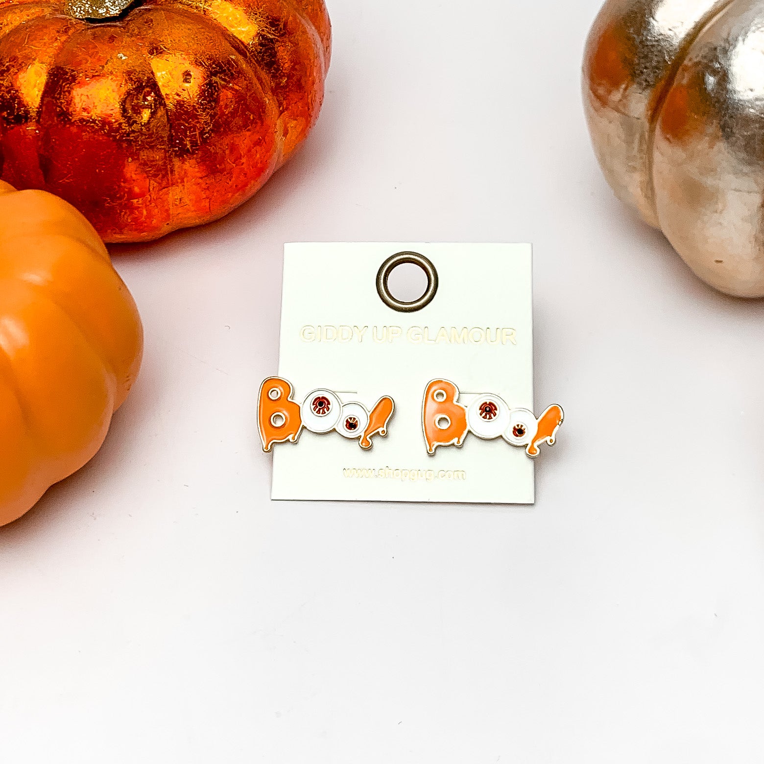 Boo Stud Earrings with Red Eyeballs in Orange. These earrings are on a white background with orange and silver pumpkins around them.