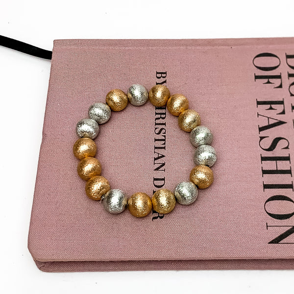 Medium mixed metals beaded bracelets. This bracelet is pictured on a pink book with a white background.