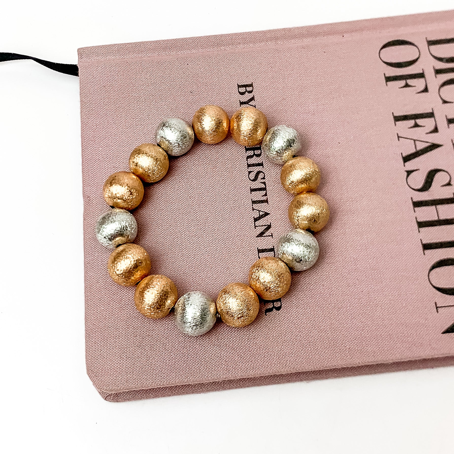 Large mixed metals beaded bracelets. This bracelet is pictured on a pink book with a white background.