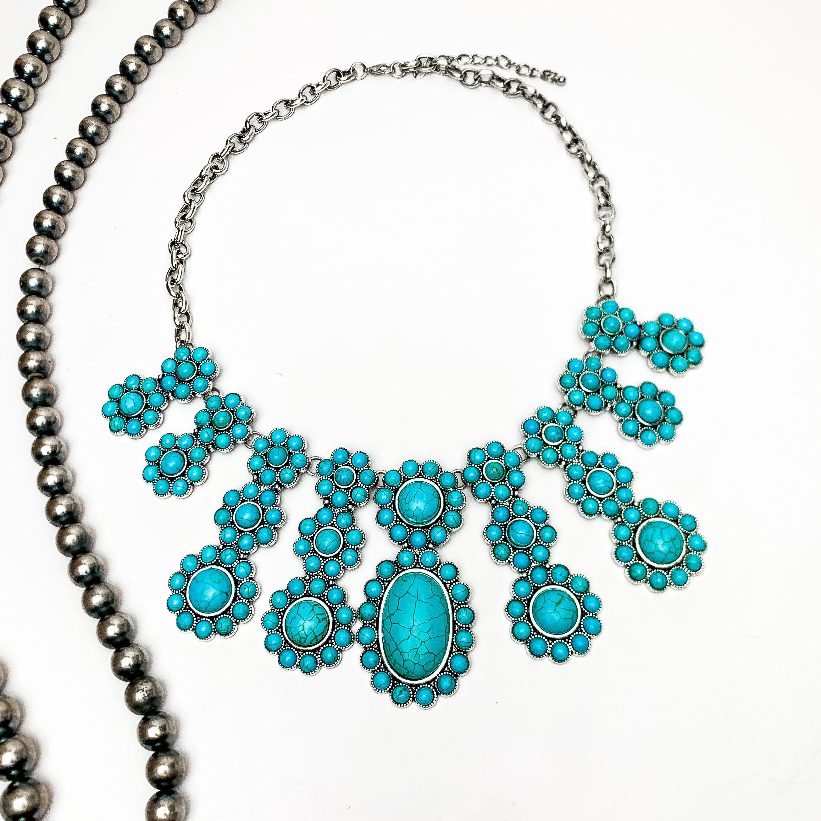 Loud and Proud Turquoise Stone Cluster Necklace. Large cluster statement necklace. This necklace is on a white background with Navajo pearls on the left side for decoration.