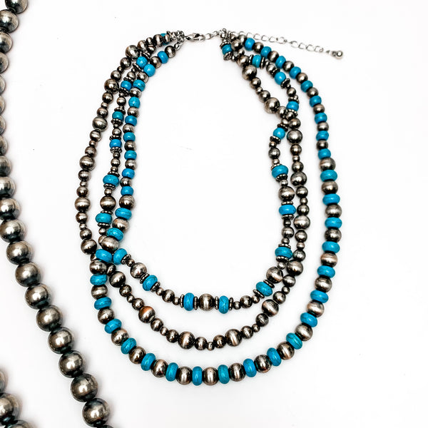 Triple Strand Turquoise and Silver Tone Beaded Necklace. This necklace is on a white background with Navajo pearls on the left side for decoration.