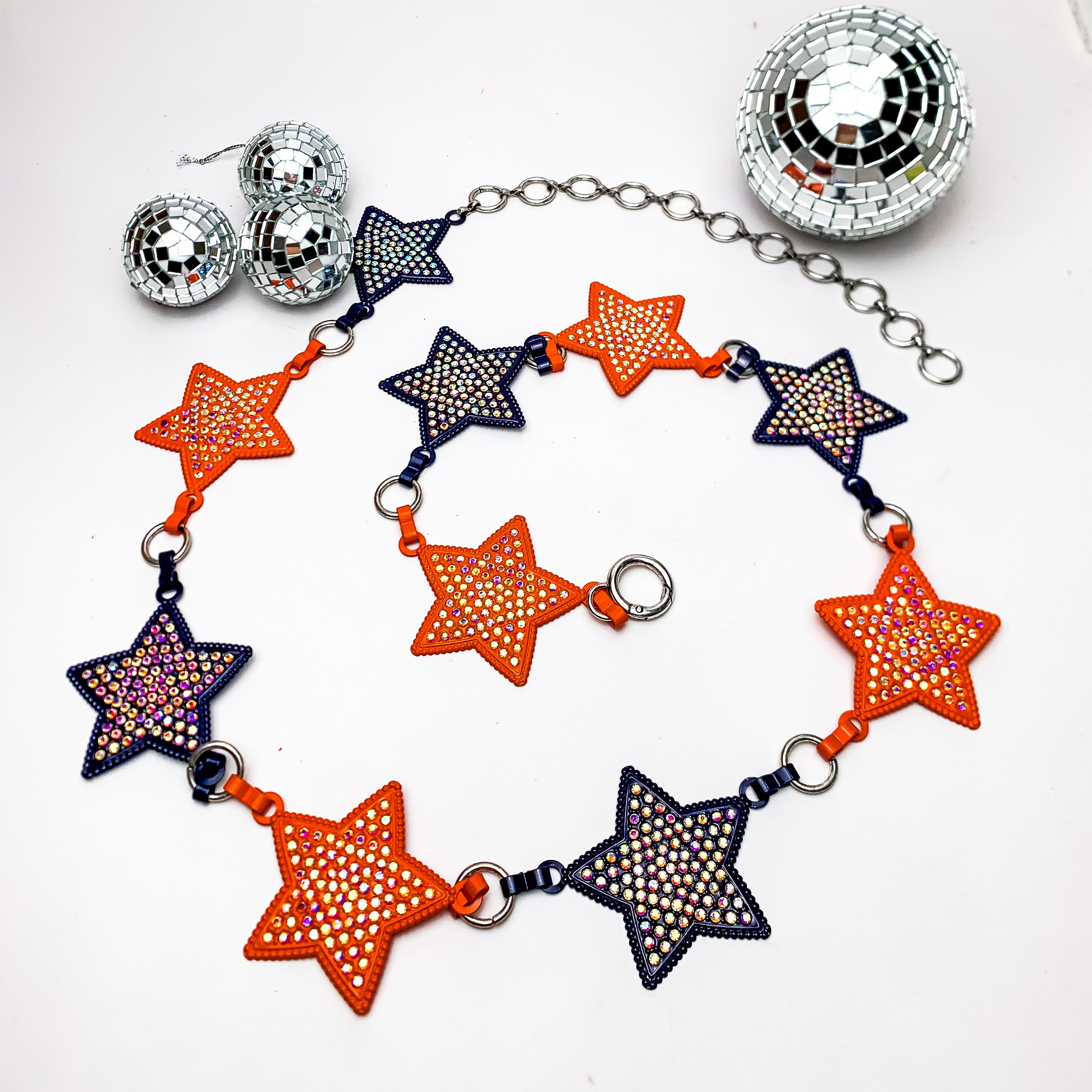Starlight Adjustable Orange and Navy Belt With Ab Crystals. This belt is on a white background with disco balls above them for decoration.