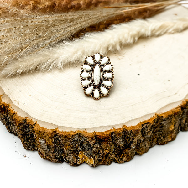 Silver Tone Flower Stone Ring in Ivory. This ring is pictured on a wood piece with feathers in the back for decoration.