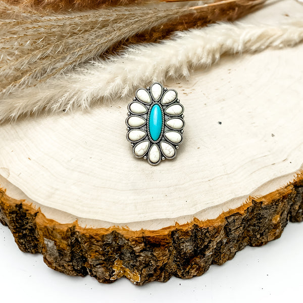 Silver Tone Flower Stone Ring in Turquoise Blue and Ivory. This cluster stone ring is pictured on a wood piece with feathers behind the ring.