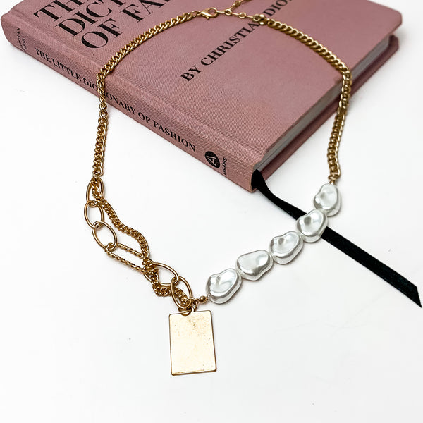 Gorgeous Pearl and Gold Tone Chain Necklace With Rectangle Charm. This necklace is pictured on a white background laying on a pink book.