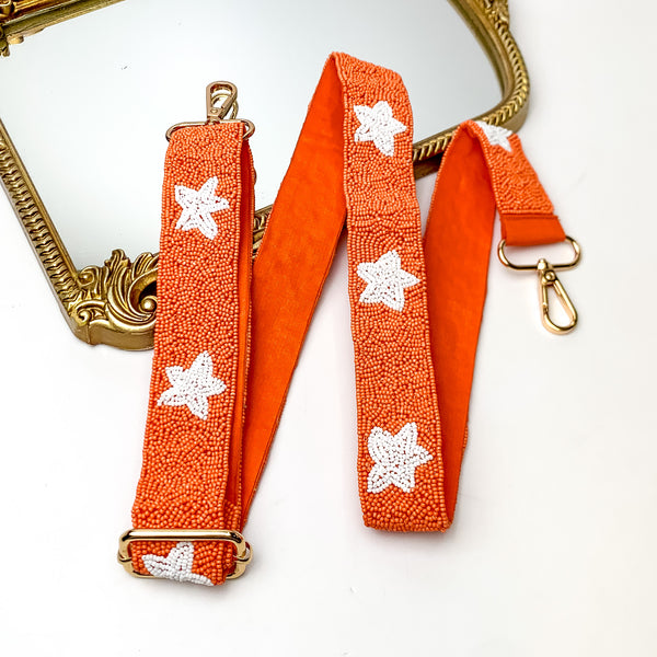 Star of the Show Beaded Adjustable Purse Strap in Orange and White. This purse strap is pictured on a white background with a gold trimmed mirror in the corner.