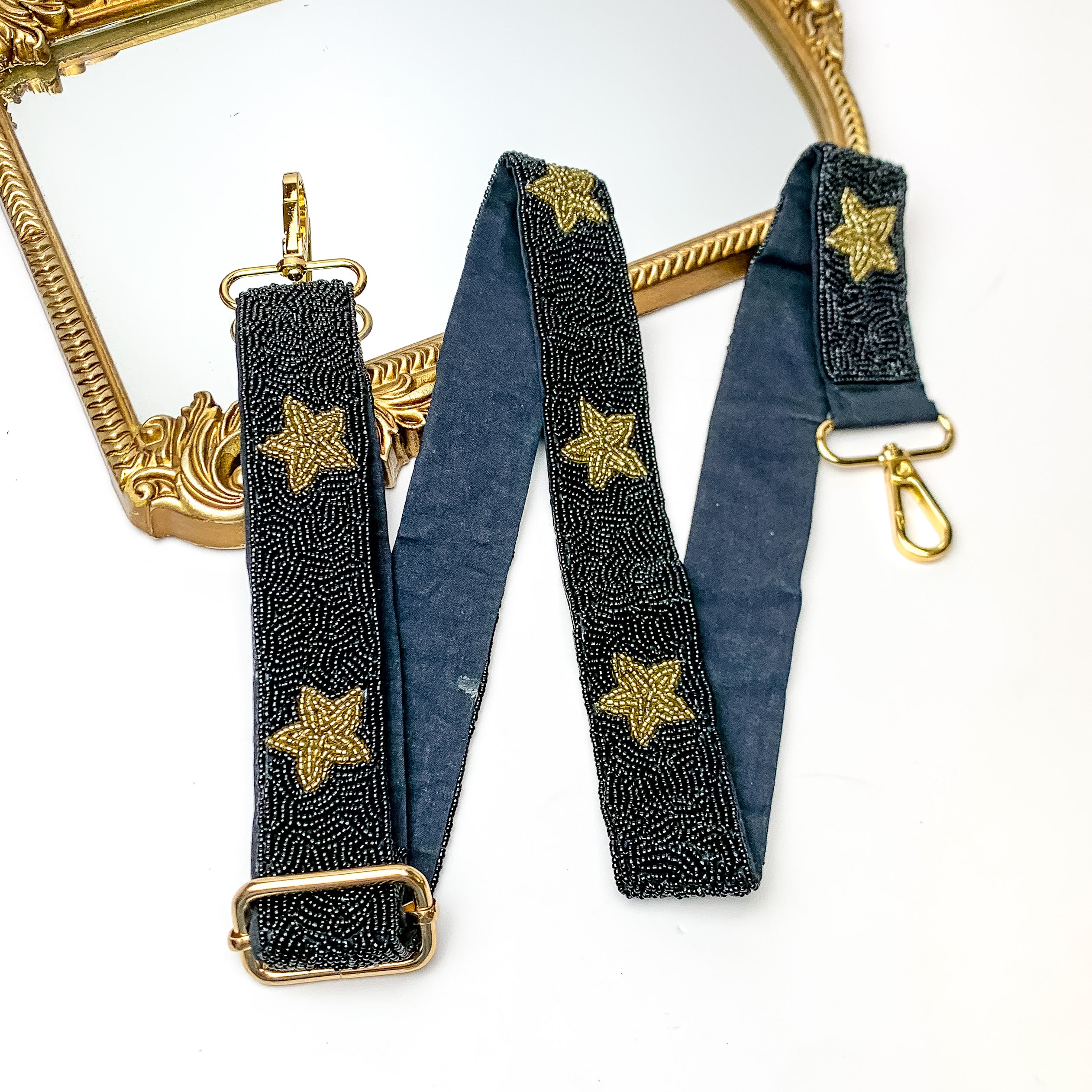 Star of the Show Beaded Adjustable Purse Strap in Black and Gold. This purse strap is pictured on a white background with a gold trimmed mirror in the corner.