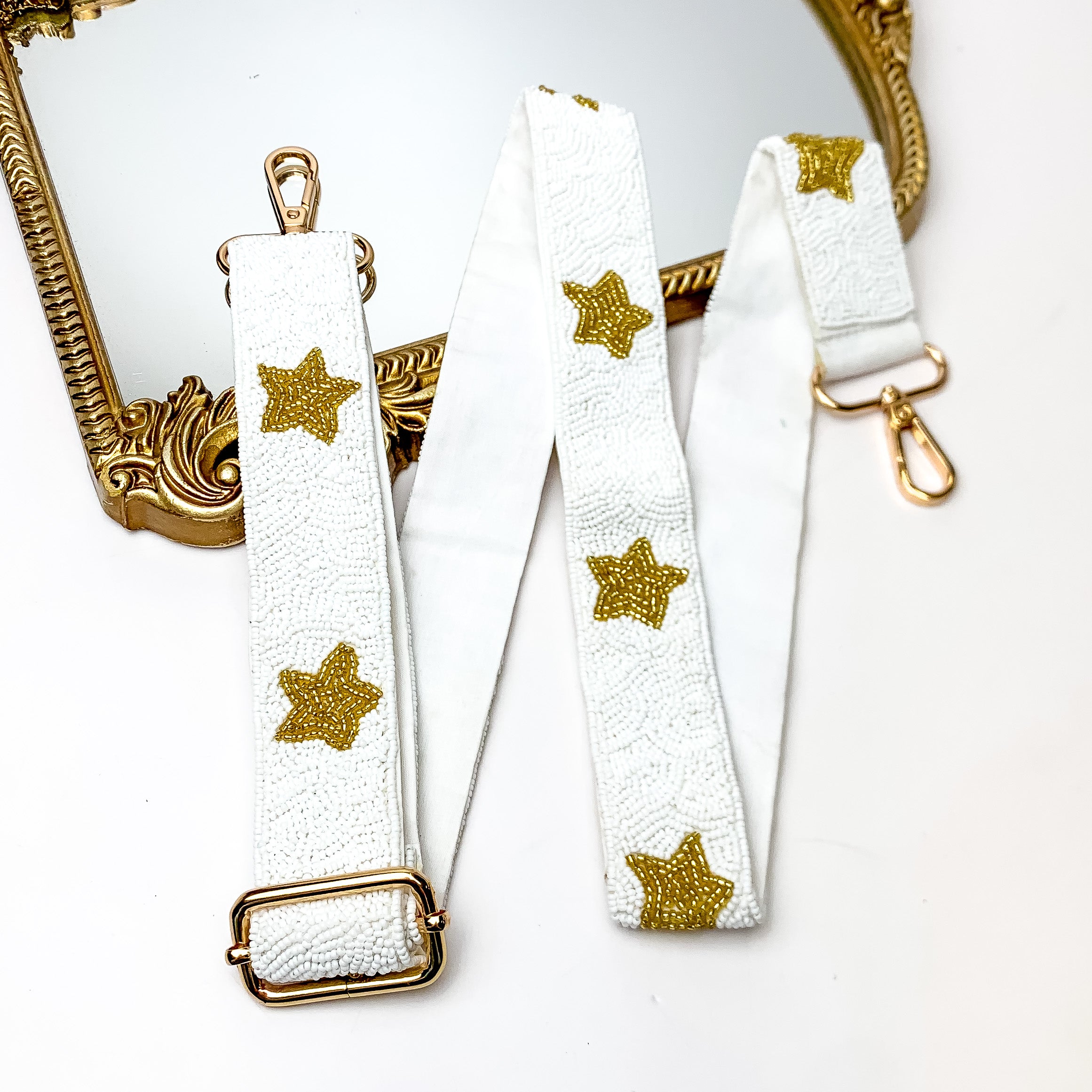 Star of the Show Beaded Adjustable Purse Strap in White and Gold. This purse strap is pictured on a white background with a gold trimmed mirror in the corner.
