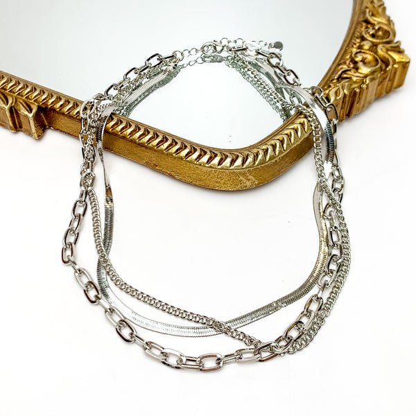 Friday Night Fun Multi Strand Chain Necklace in Silver Tone. This silver tone necklace is on a white background with part of it on a gold trimmed mirror.