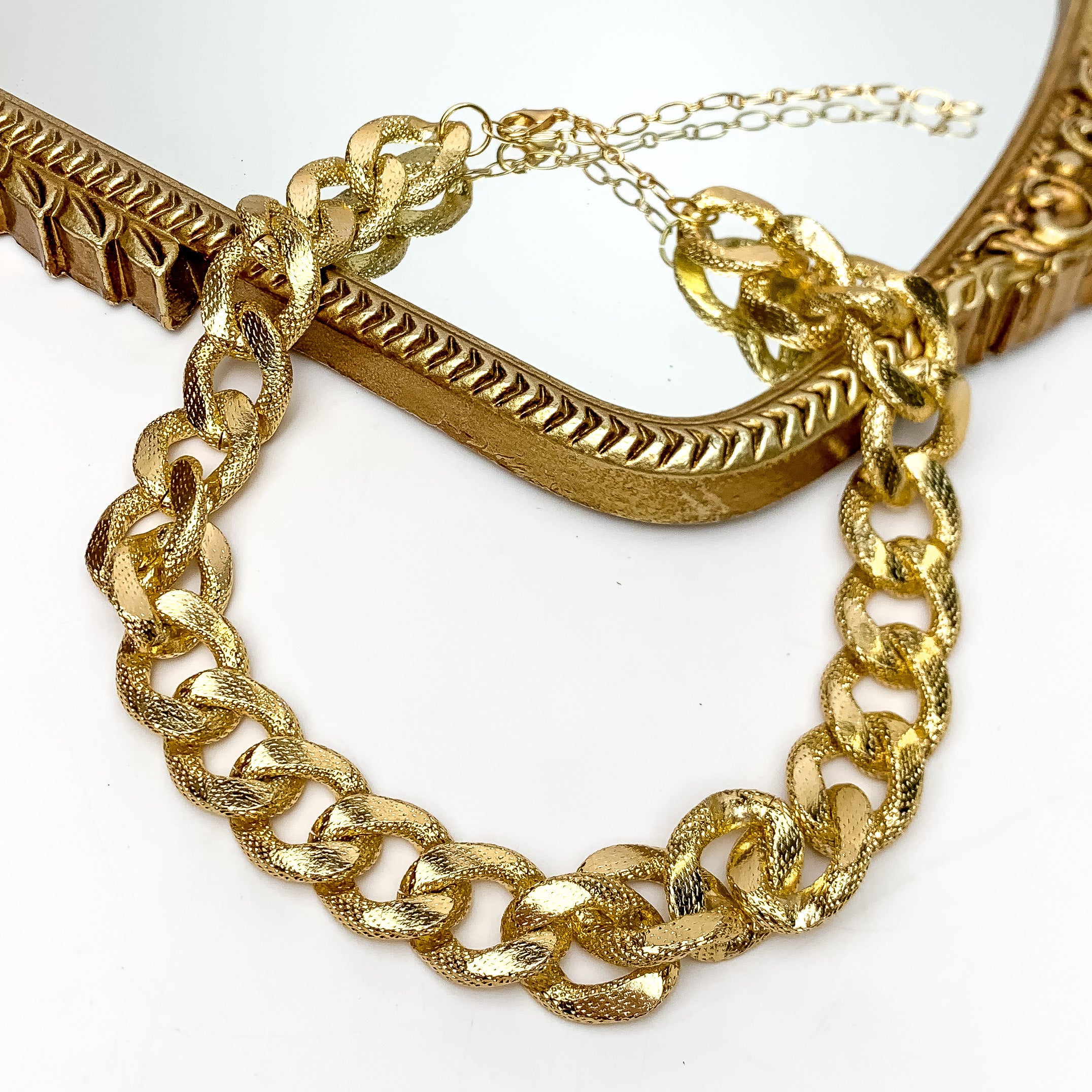 The Go To Gold Tone Chain Necklace. This necklace is pictured on a white background with part of the chain on a gold trimmed mirror.