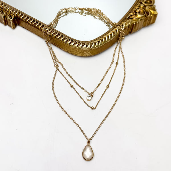Plain as Day Multi Strand Gold Tone Chain Necklace. This necklace is pictured on a white background with part of it on a gold trimmed mirror.
