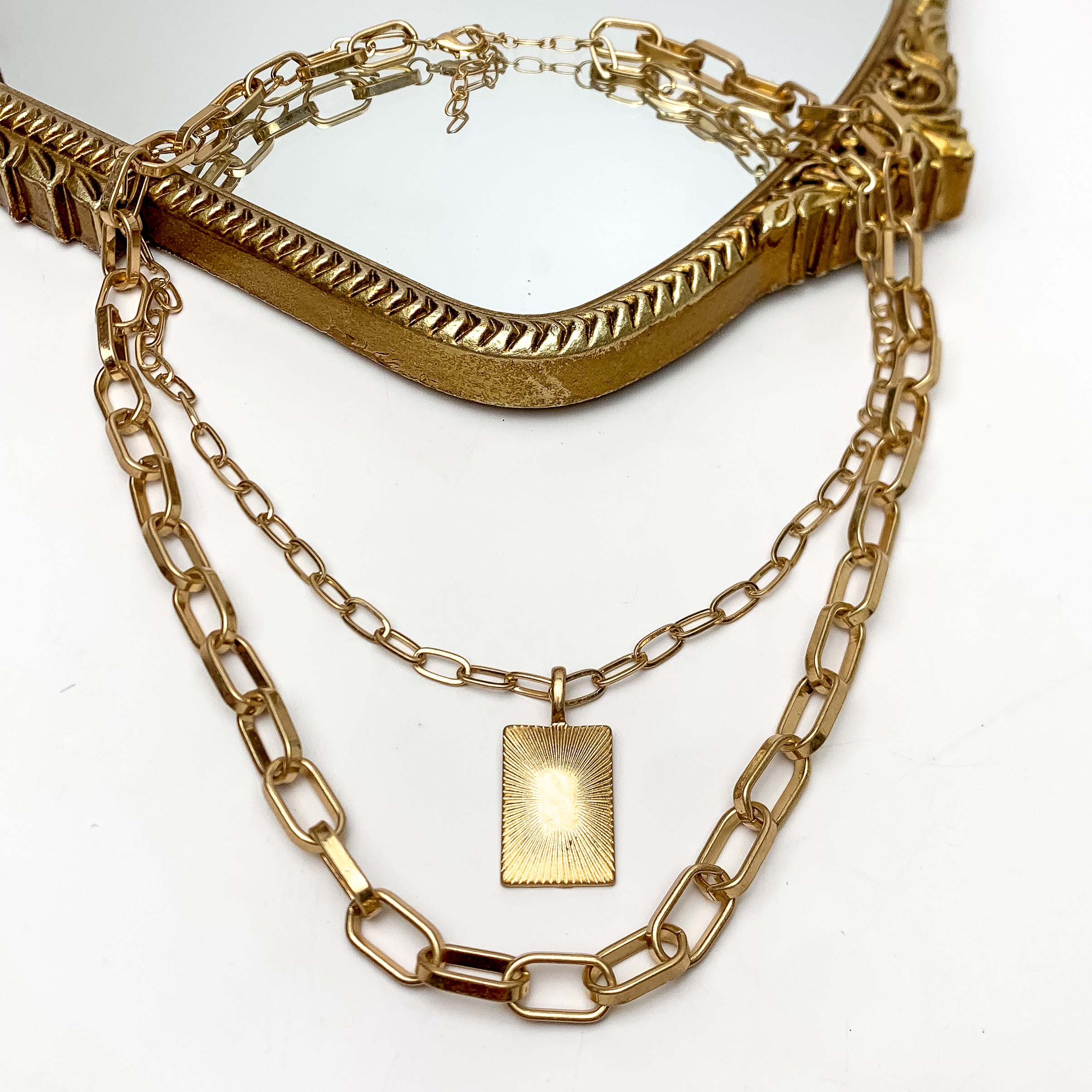 Better Than Ever Multi Strand Gold Tone Chain Necklace. This necklace is pictured on a white background with part of it on a gold trimmed mirror.