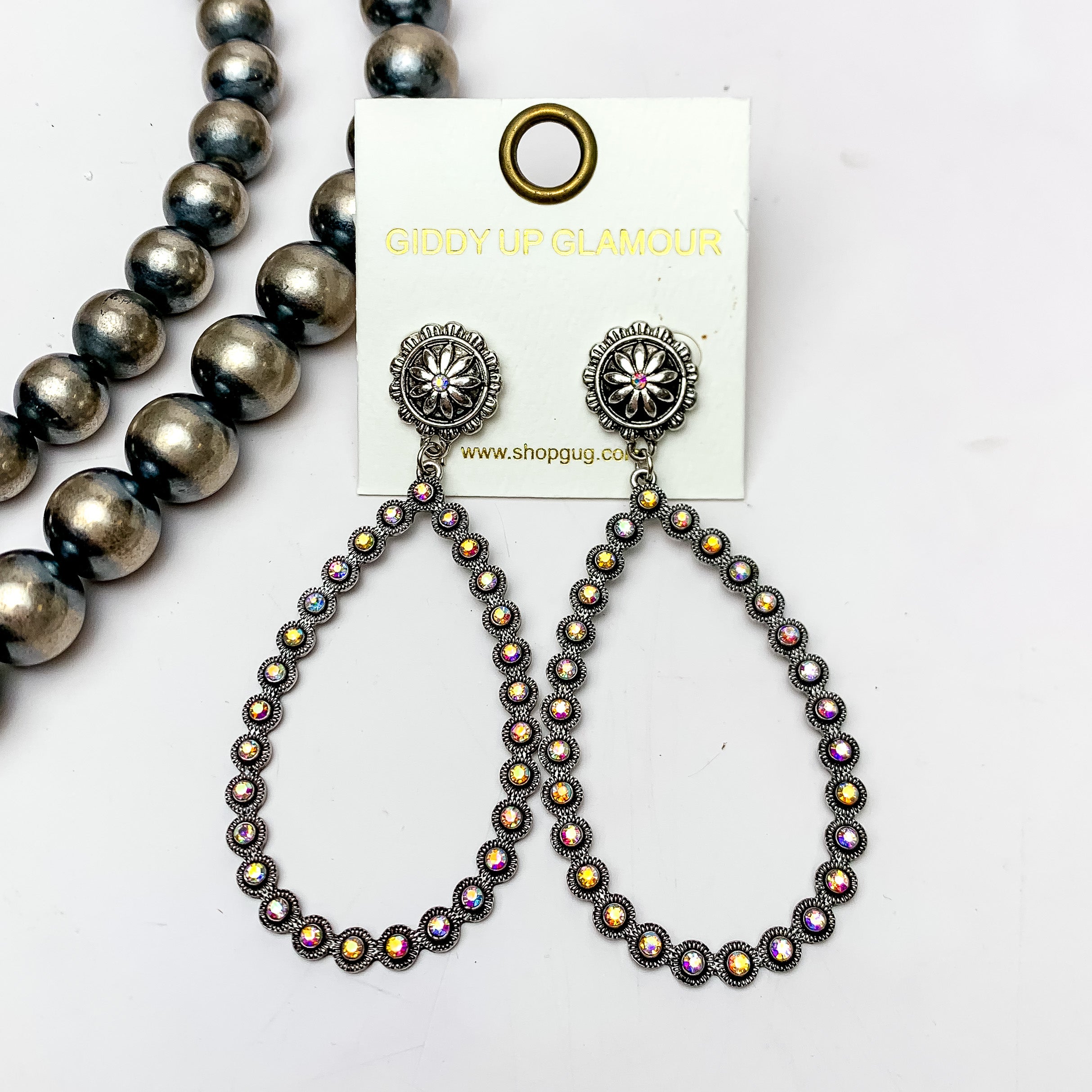 AB Crystal Open Teardrop Earrings in Silver Tone. Pictured on a white background with Navajo pearls on the left side.