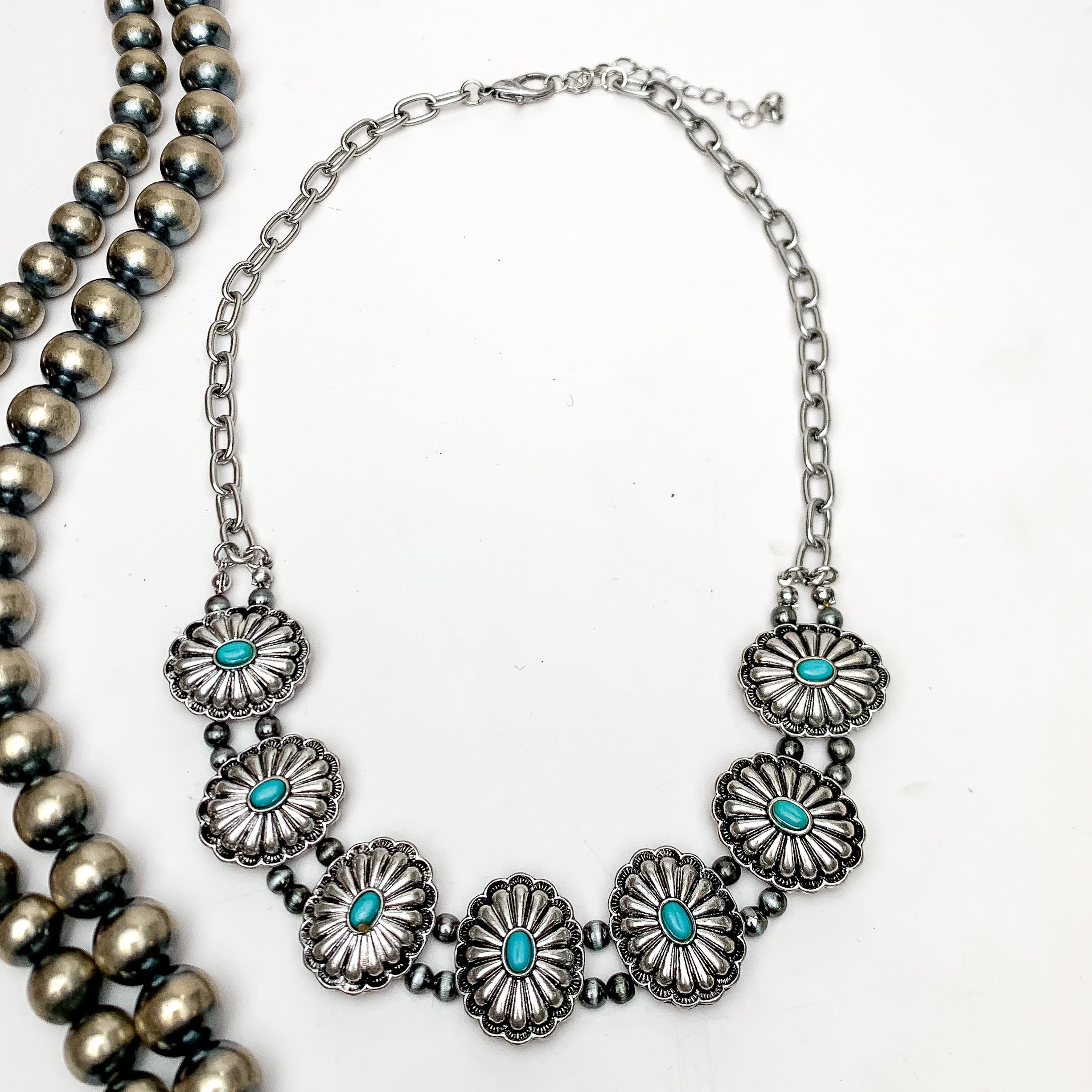 Silver Tone Flower Concho Necklace With Turquoise Blue Stones. This necklace is on a white background with Navajo pearls on the left.