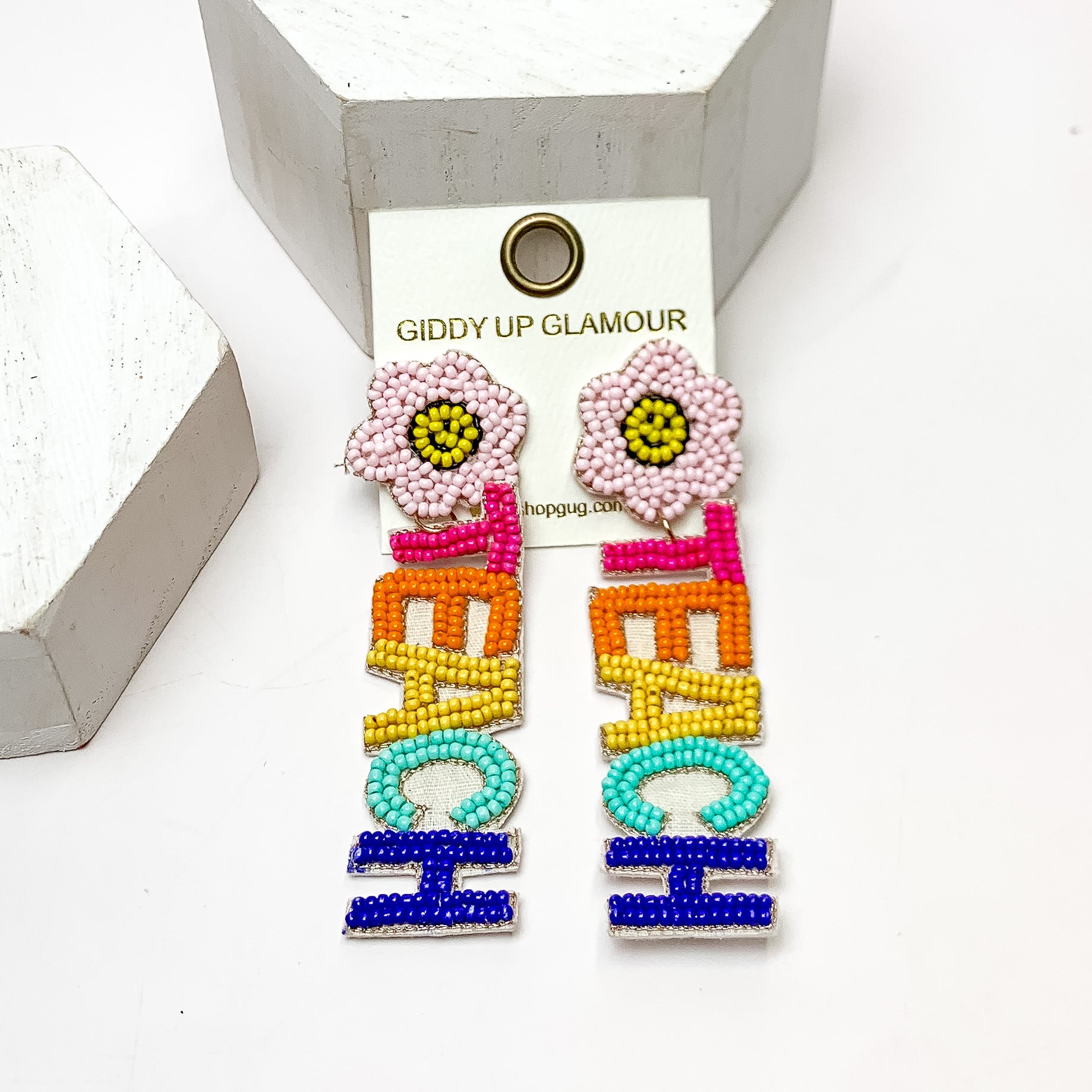 Multicolor "TEACH" Beaded Earrings With Flower Posts. These earrings are on a white background and have white posts around them.