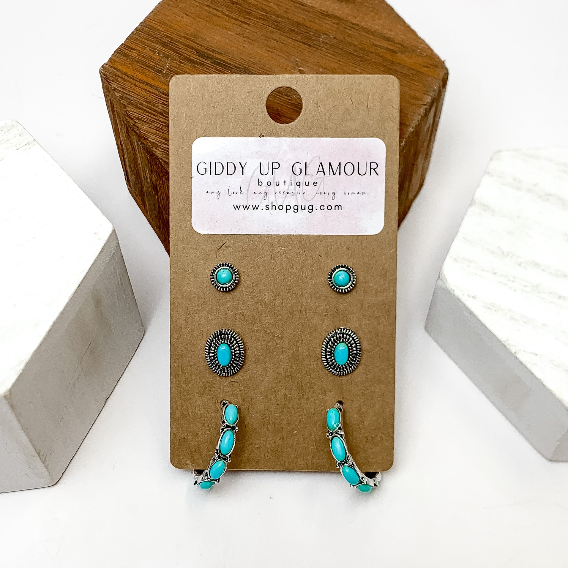 Set Of Three | Stud and Hoop Silver Tone Earring Set in Turquoise. These earring are pictured laying against a wooden block with a white background.