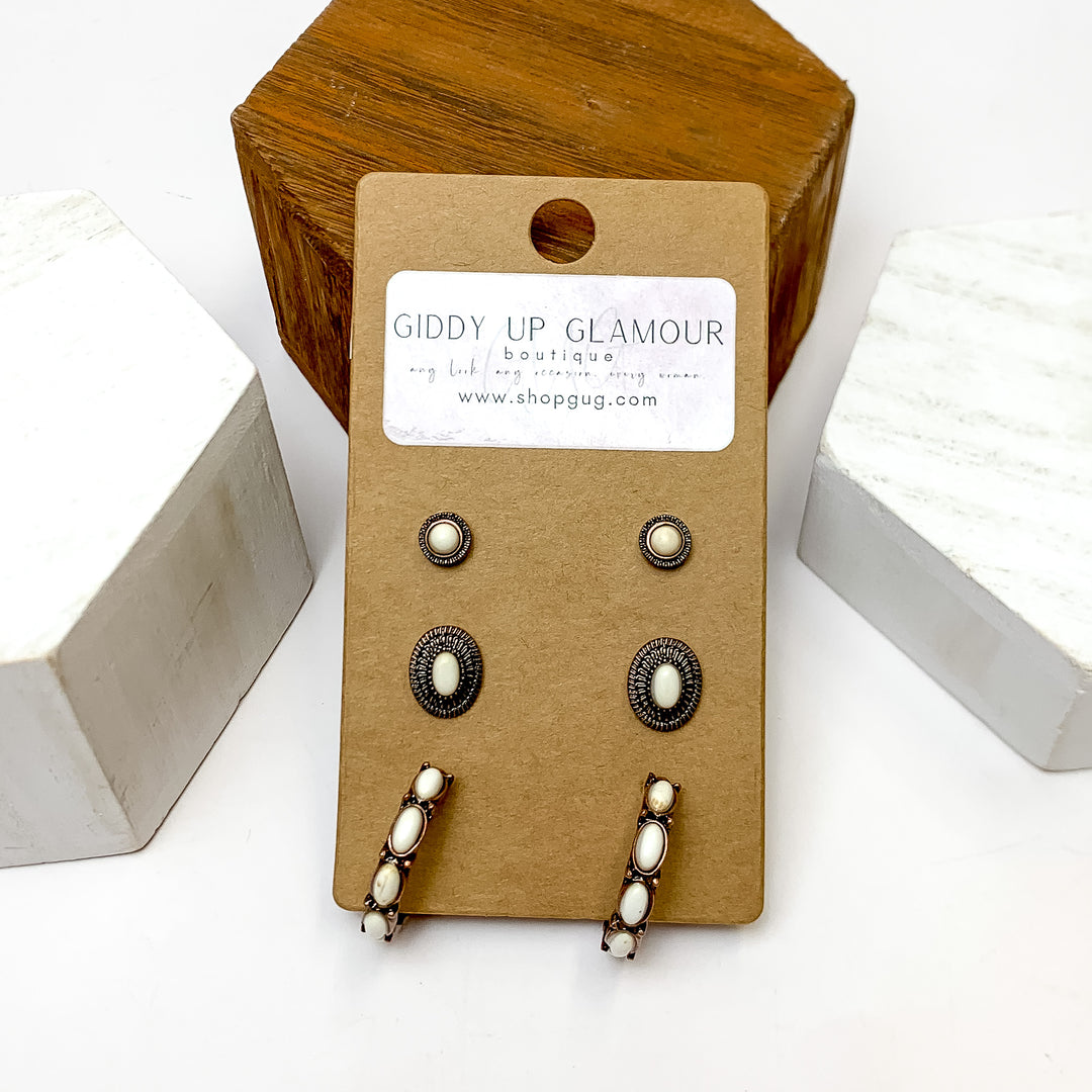Set Of Three | Stud and Hoop Copper Tone Earring Set in Ivory. These earring are pictured laying against a wooden block with a white background.