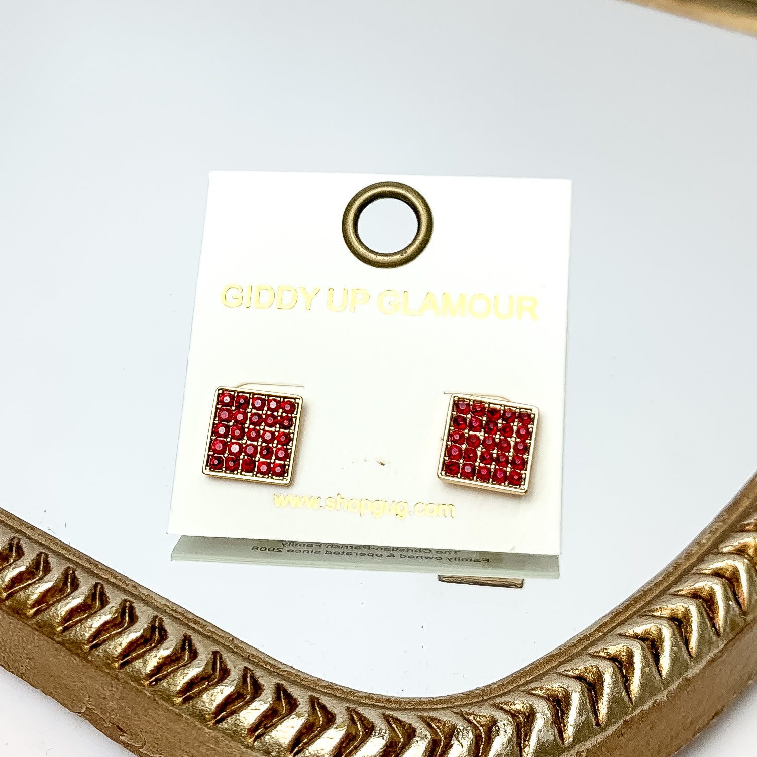 Square Maroon Crystal Stud Earrings in Gold Tone. These earrings are pictured on a white background with a gold frame around. 