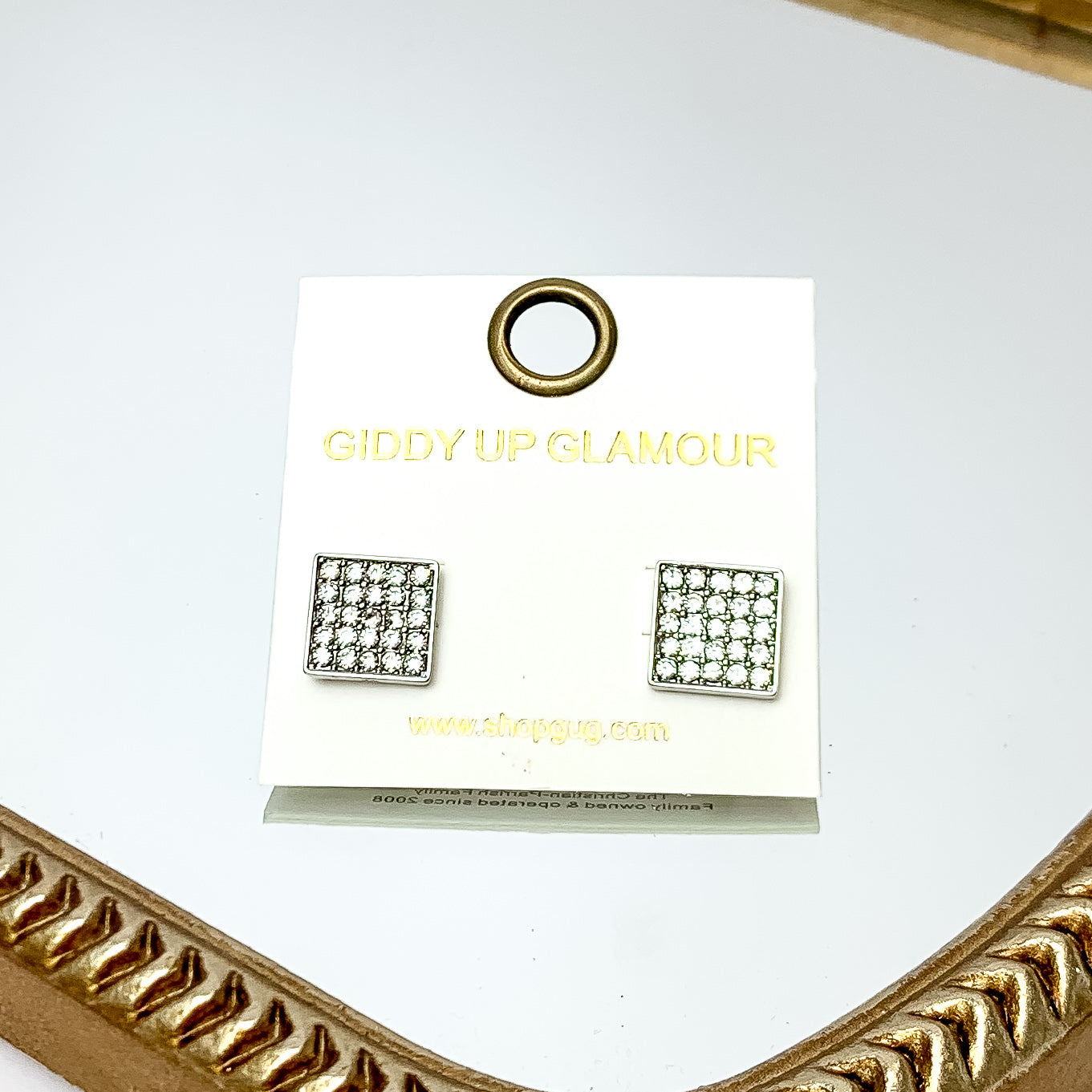 Square Clear Crystal Stud Earrings in Silver Tone. These earrings are pictured on a white background with a gold frame around.