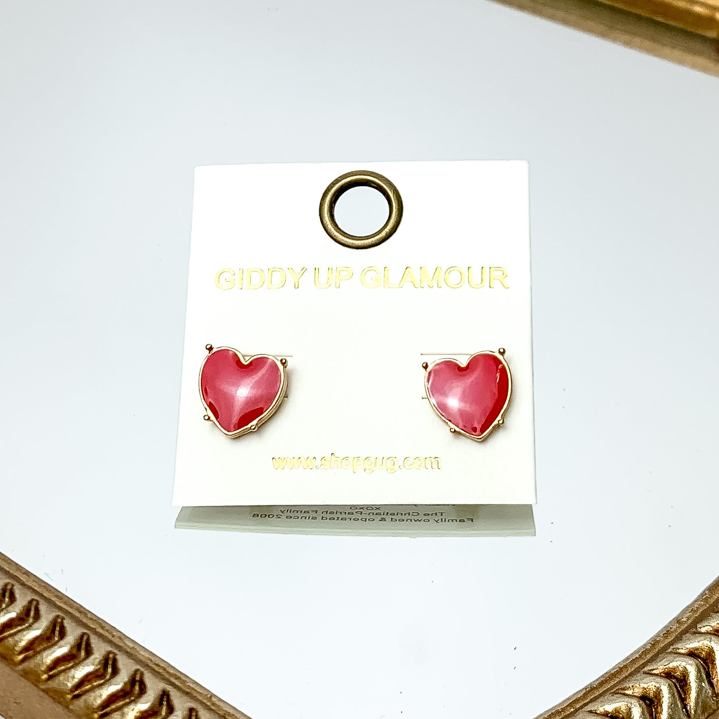 Gold Tone Heart Stud Earrings in Red. These earrings are pictured on a white background with a gold frame around.