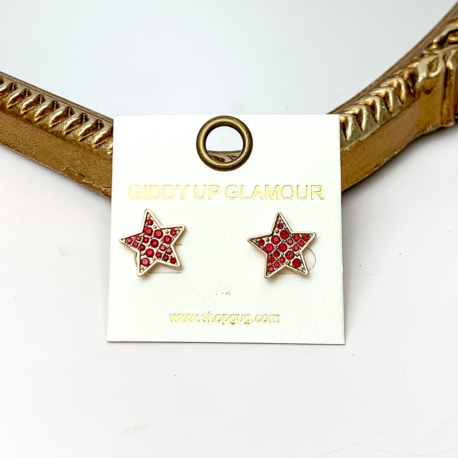 Star Maroon Crystal Stud Earrings in Gold Tone. These earrings are pictured on a white background with a gold frame around.