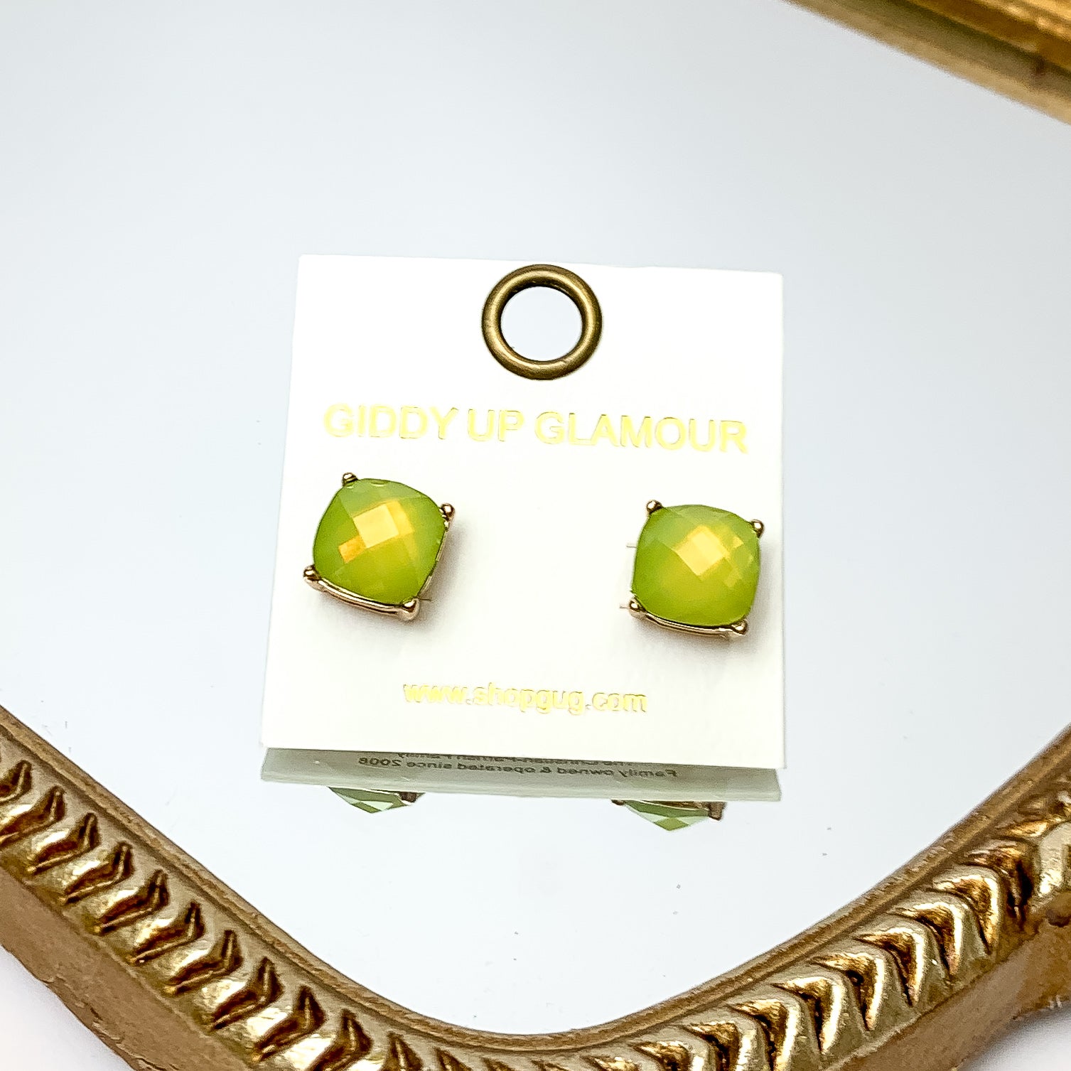 Large Crystal Stud Earrings in Light Green. These earrings are pictured laying on a gold trimmed mirror.