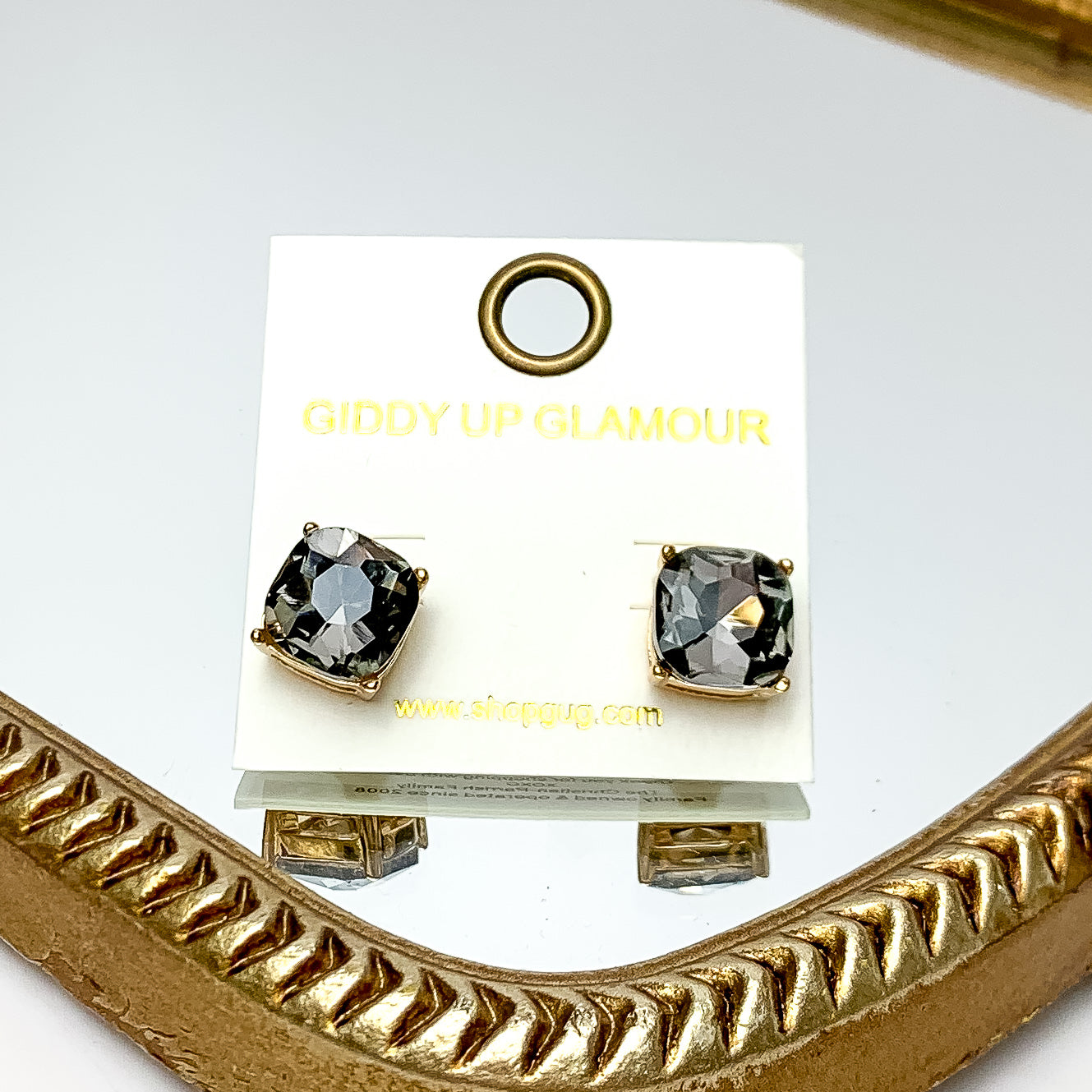 Large Crystal Stud Earrings in Grey. These earrings are pictured laying on a gold trimmed mirror.