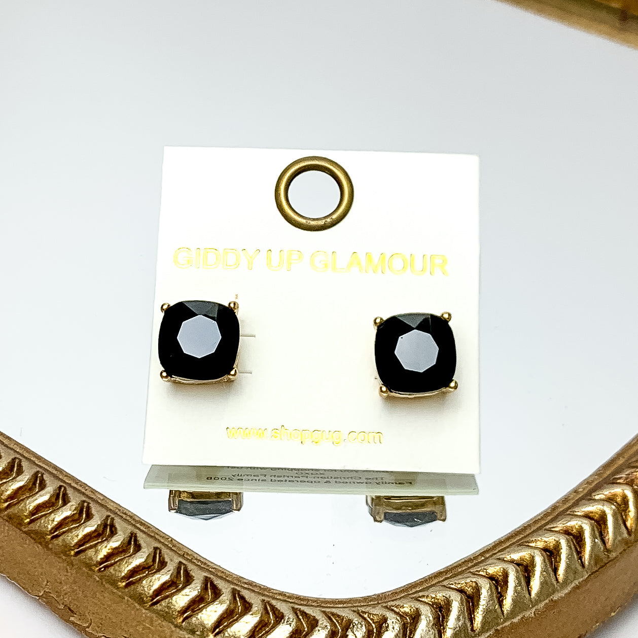 Large Crystal Stud Earrings in Black. These earrings are pictured laying on a gold trimmed mirror.