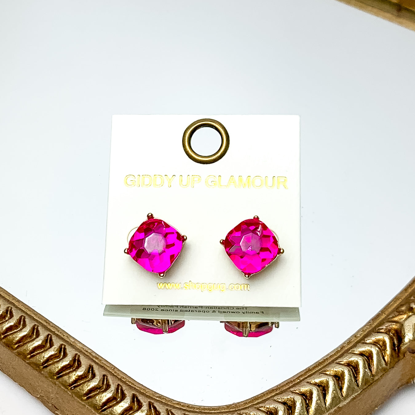 Large Crystal Stud Earrings in Hot Pink. These earrings are pictured laying on a gold trimmed mirror.