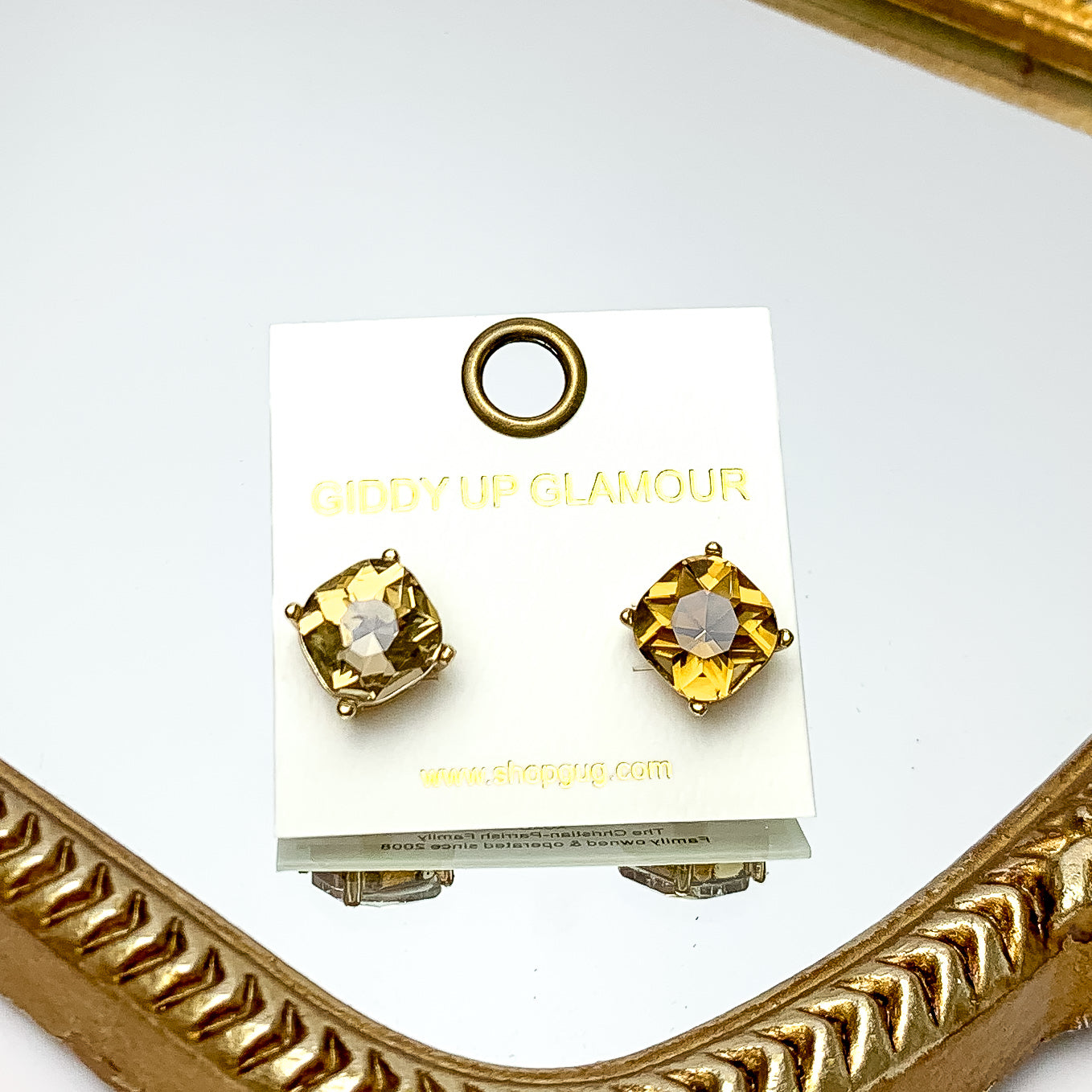 Large Crystal Stud Earrings in Olive Green. These earrings are pictured laying on a gold trimmed mirror.