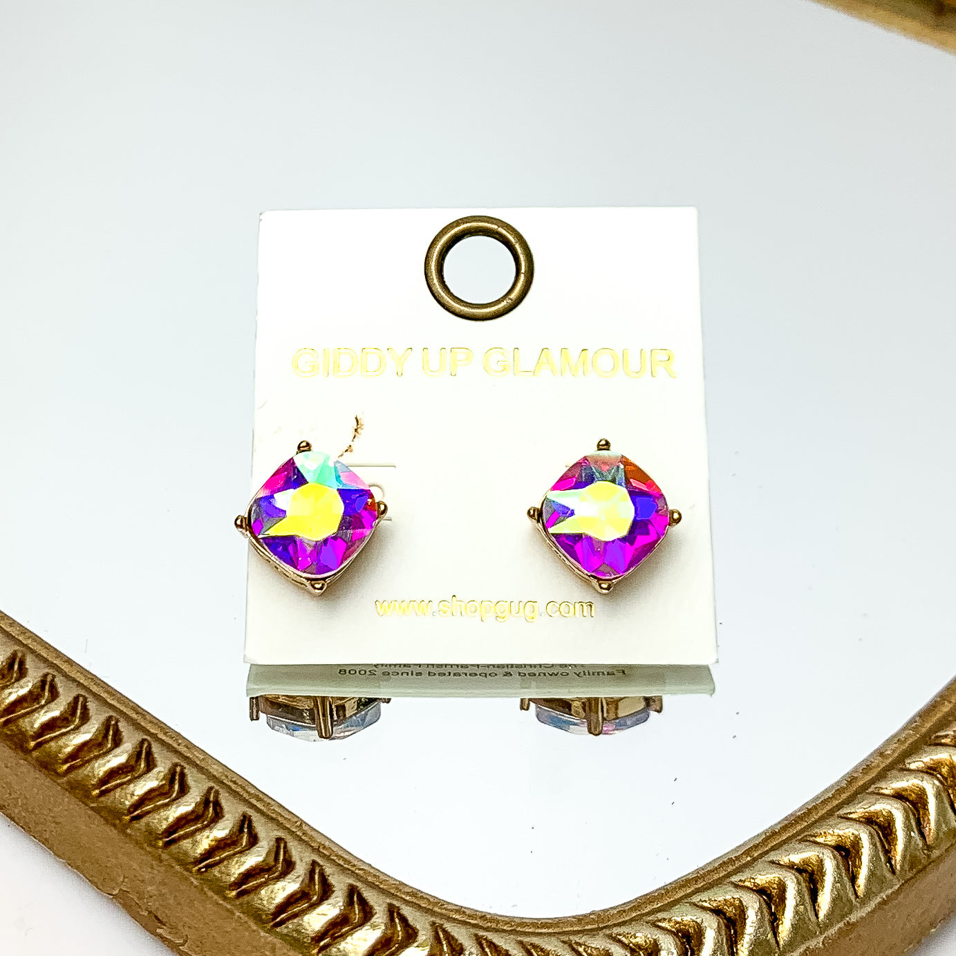 Large AB Crystal Stud Earrings in Gold Tone. These earrings are pictured laying on a gold trimmed mirror.