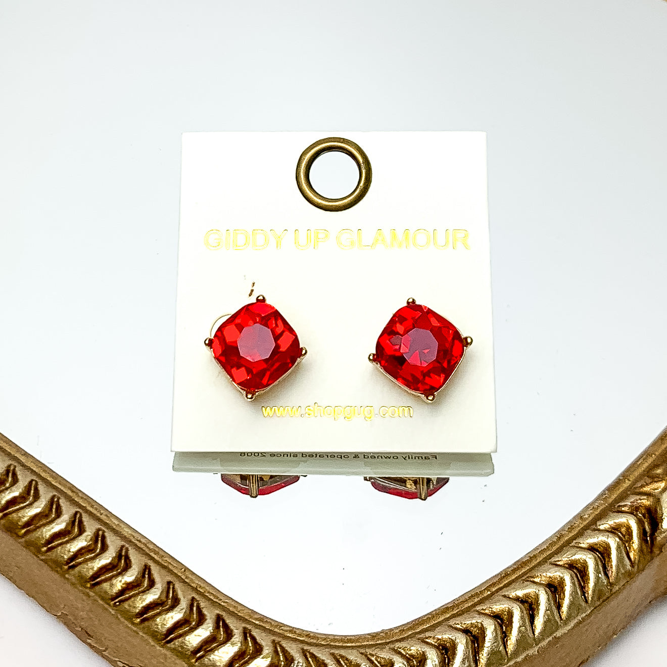 Large Crystal Stud Earrings in Red. These earrings are pictured laying on a gold trimmed mirror.