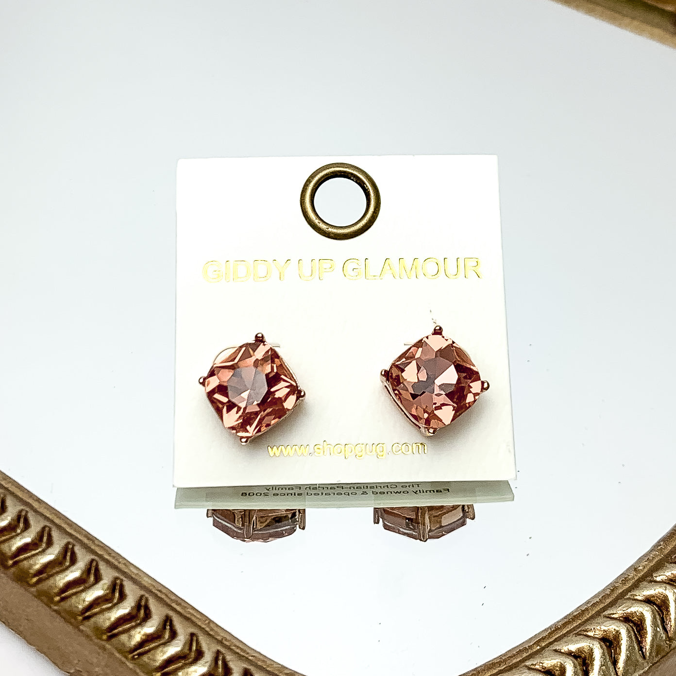 Large Crystal Stud Earrings in Light Pink. These earrings are pictured laying on a gold trimmed mirror.