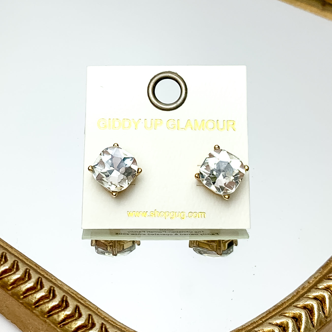 Large Clear Crystal Stud Earrings in Gold Tone. These earrings are pictured laying on a gold trimmed mirror.