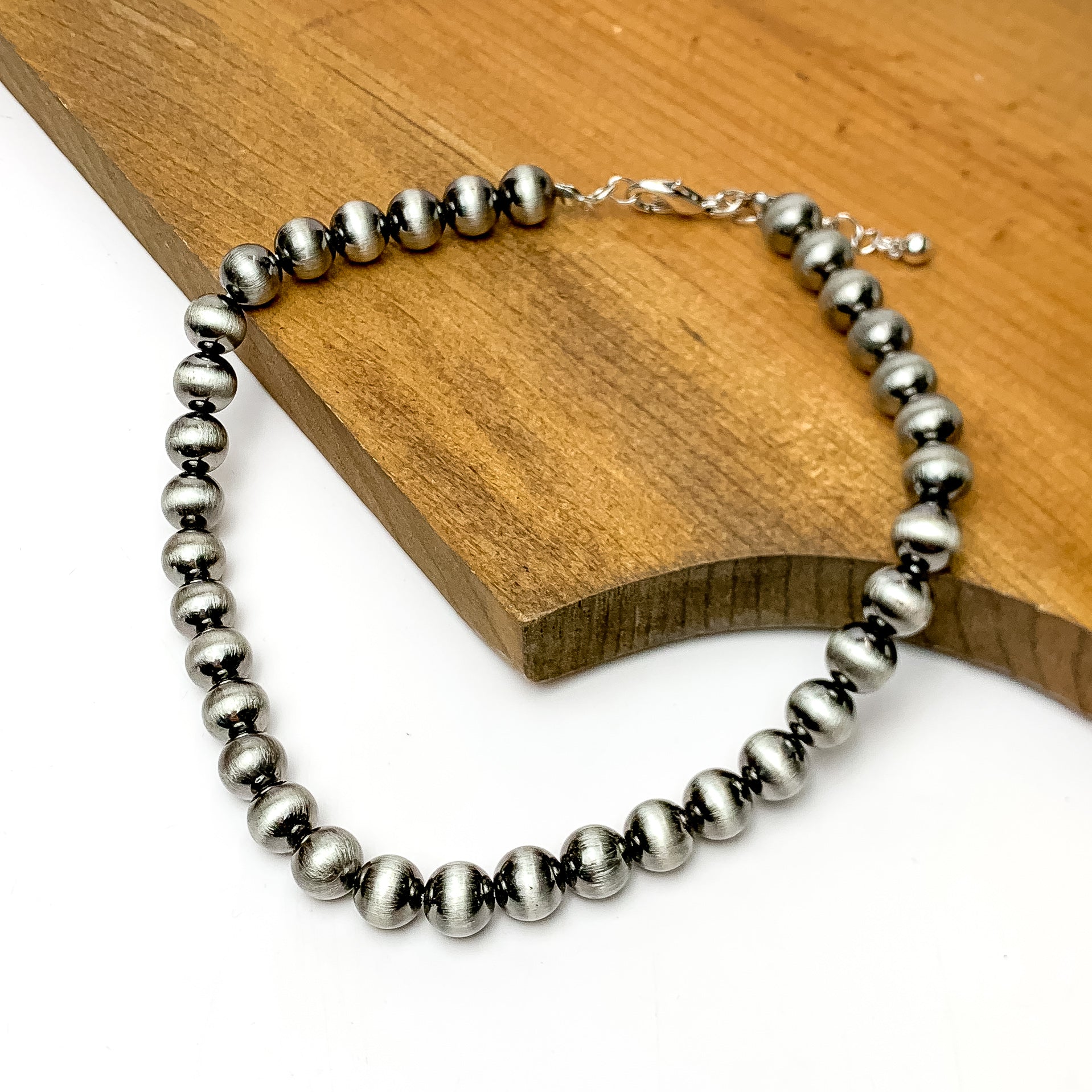 Small Faux Navajo Pearls Necklace in Silver Tone. This necklace is pictured on a wood piece with a white background.