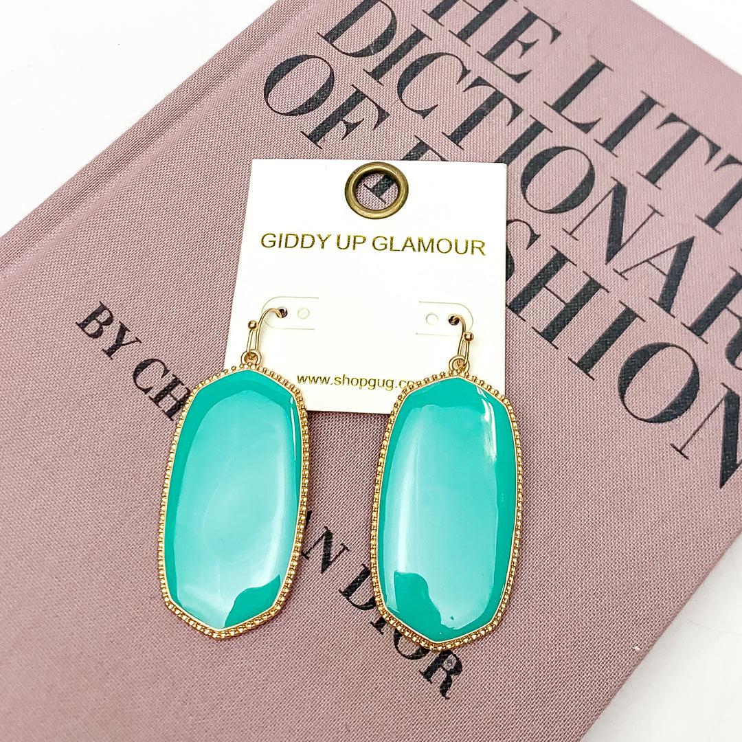 Southern Charm Oval Earrings in Grey. These earrings are laying on a pink book with a white background behind the book.