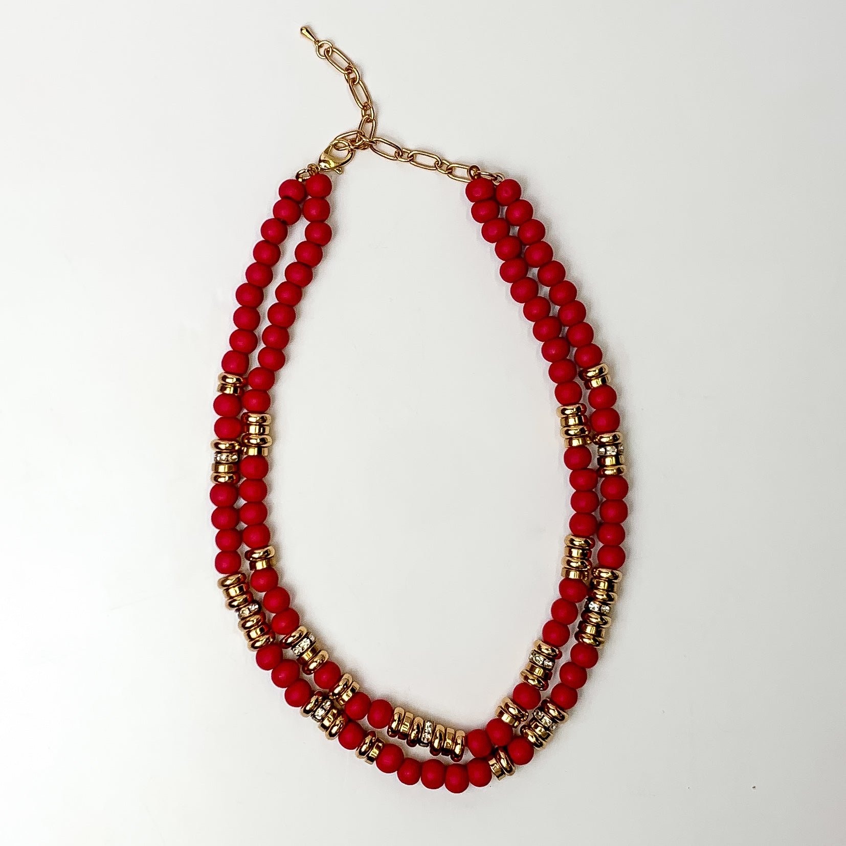 This layered necklace in red has gold spacers. It is taken with a white background.