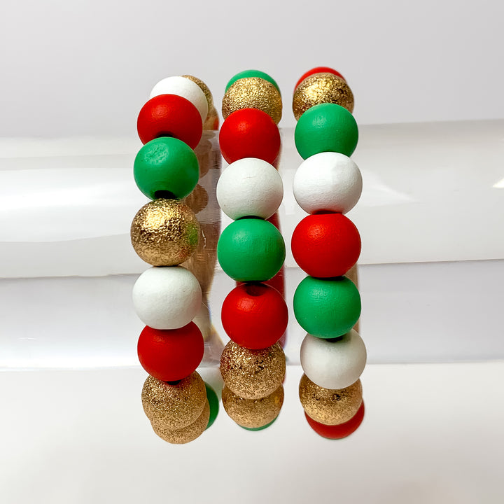 This set of 3 bracelets in the colors red, green, and white are placed on a bracelet display featuring a white background.