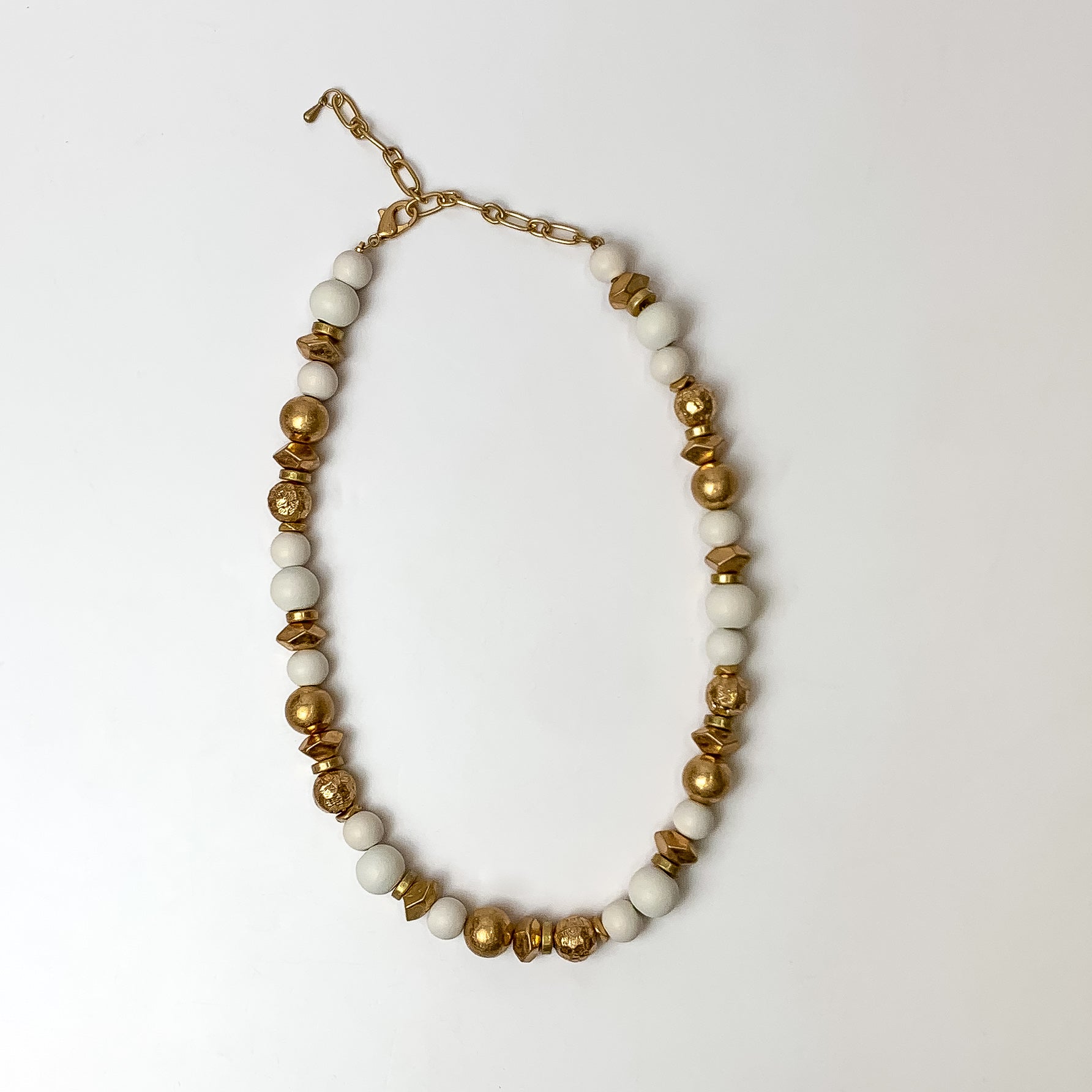 This texture beaded necklace with gold tone and white beads are placed on a white background.