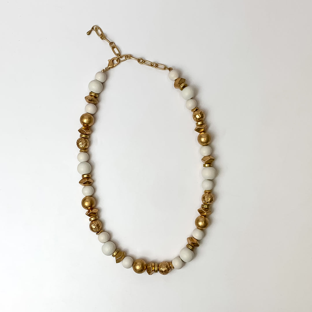 This texture beaded necklace with gold tone and white beads are placed on a white background.