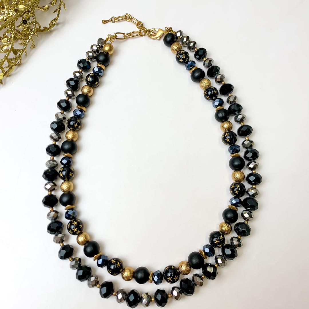 This NYC Dream Multi Strand Black Necklace is pictured on a white background with gold tinsel in the top  left hand corner.