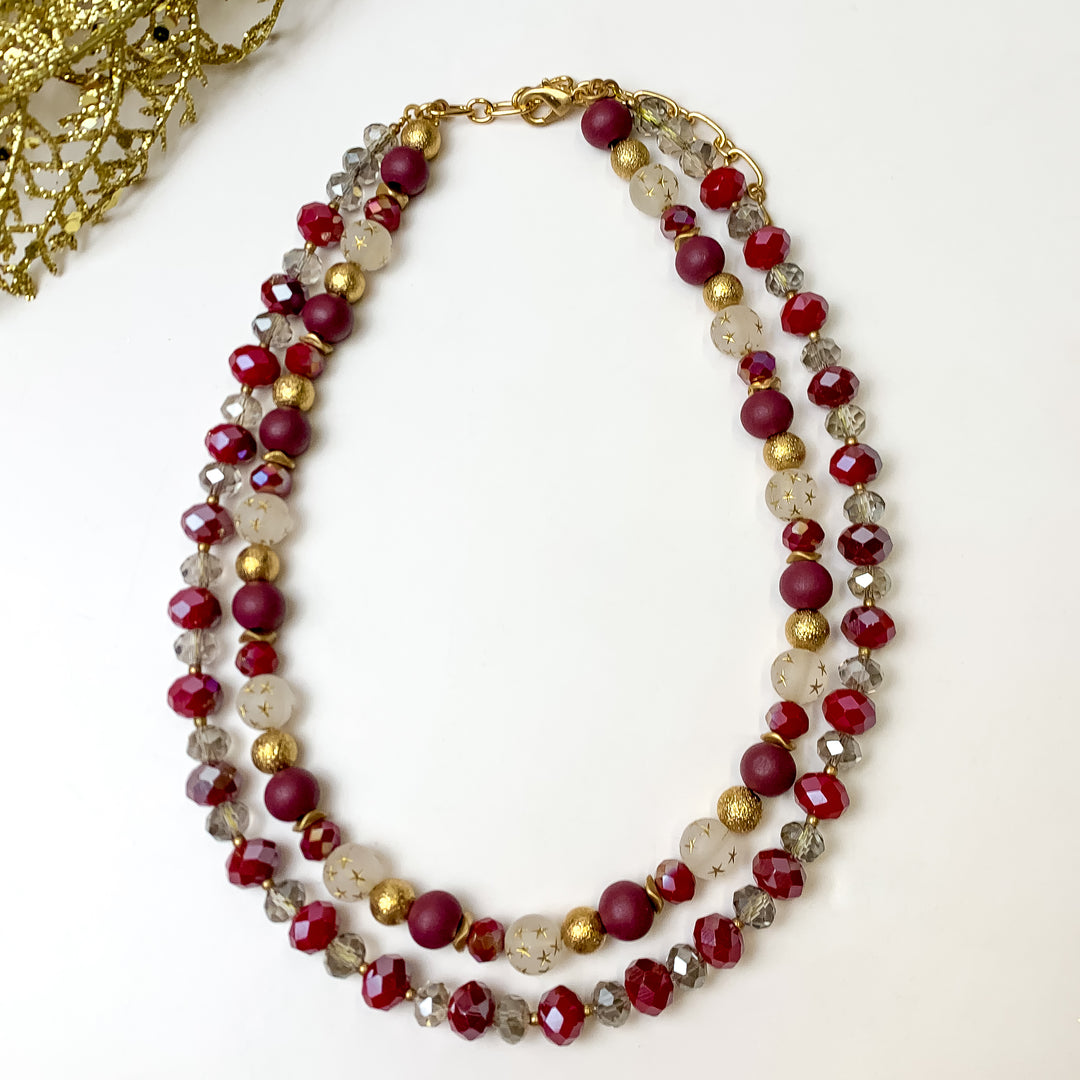This NYC Dream Multi Strand Plum Necklace is pictured on a white background with gold tinsel in the top left corner.