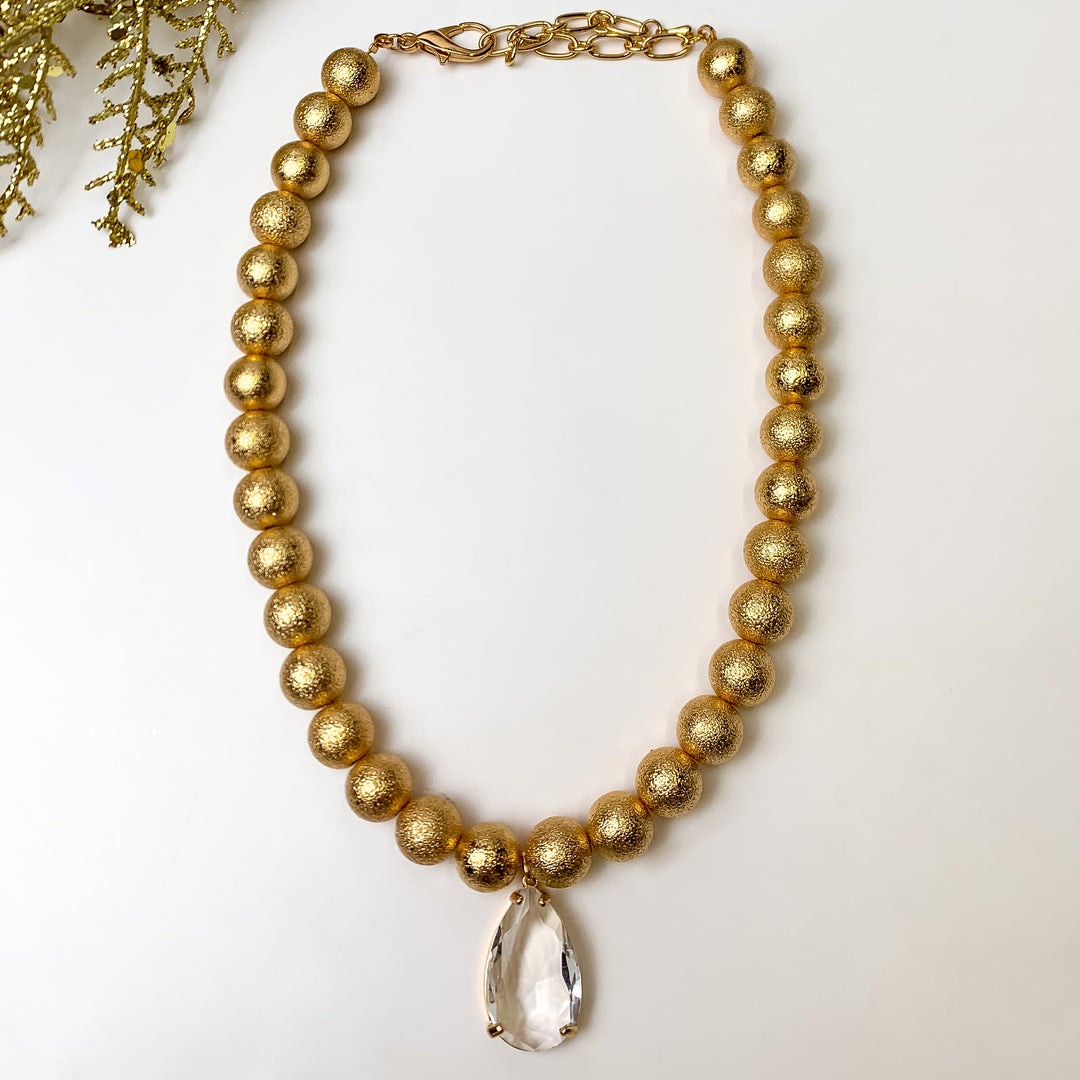 This Spotlight Special Gold Tone Teardrop Necklace is pictured on a white background with gold tinsel in the top left corner.