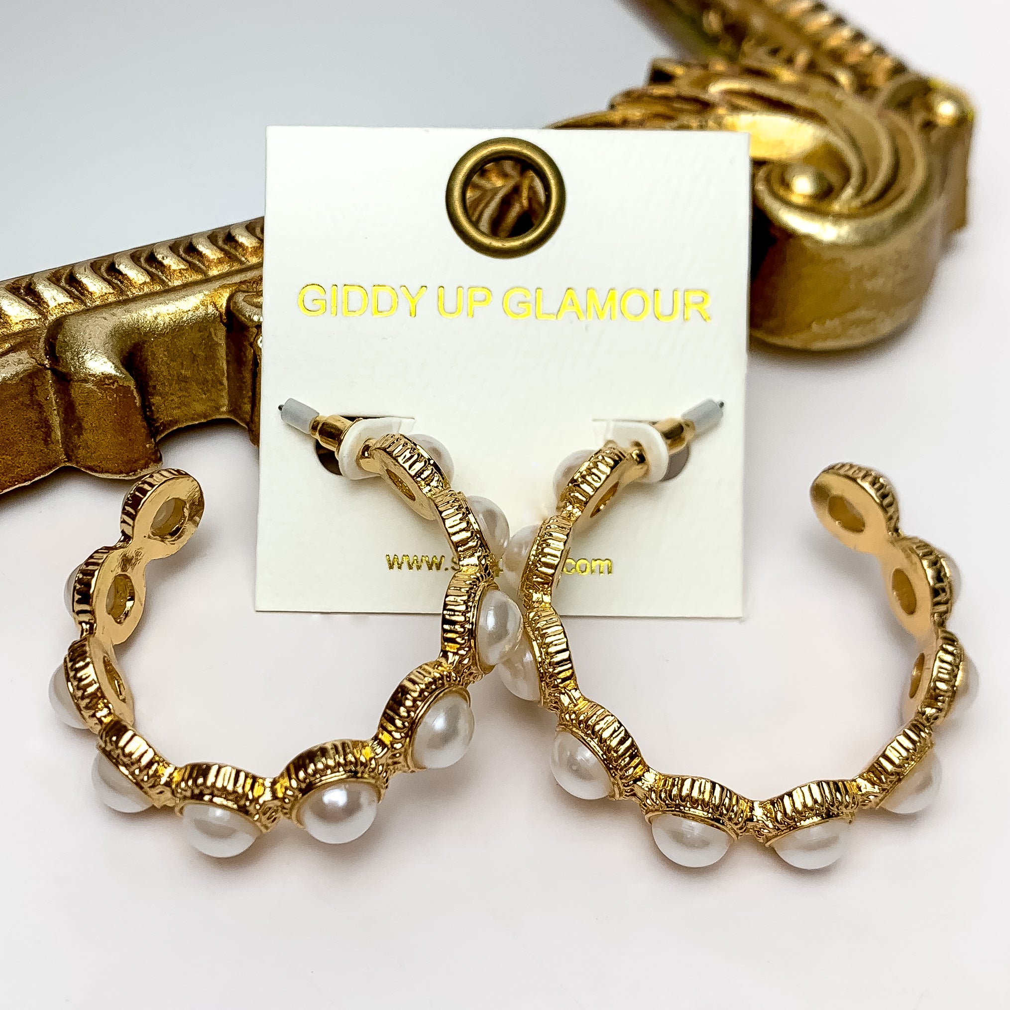 These Gold Tone Pearl Beaded Hoop Earrings in Ivory are placed on an ivory earring card. They are pictured on a white background with a gold mirror.