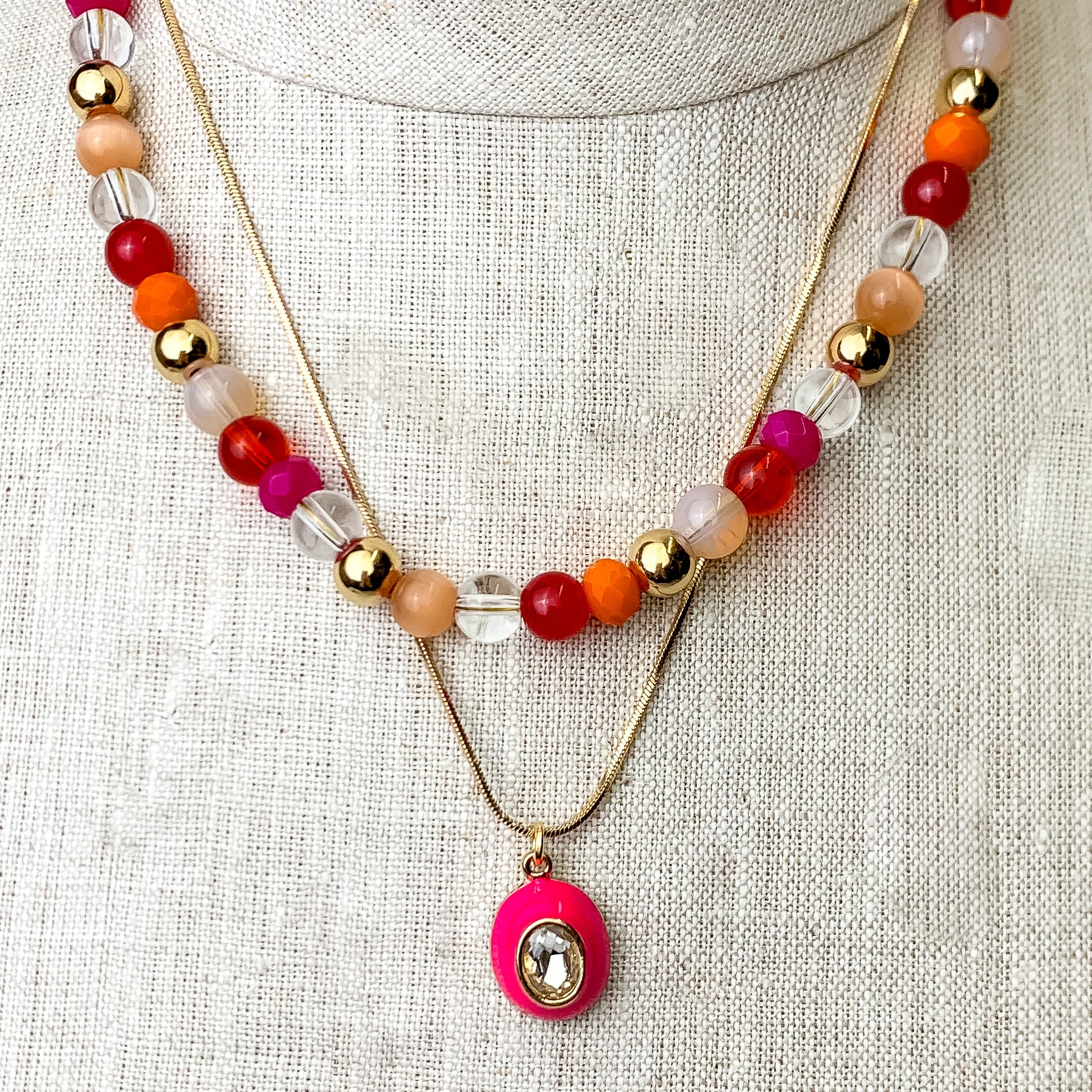 This Multicolored Layering Necklace with an Oval Pendant id pictured on an ivory mannequin with a white background.